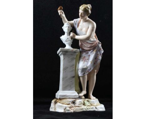 A CONTINENTAL PORCELAIN FIGURINE depicting a classical sculptress at work, classically draped, working with hammer &amp; chis