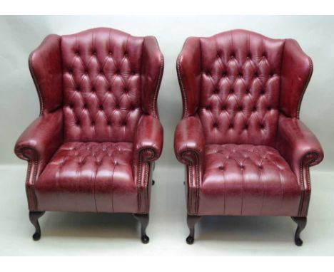 A PAIR OF LATE 20TH CENTURY DISTRESSED OX BLOOD LEATHER UPHOLSTERED WINGBACK ARMCHAIRS, having button backs and seat pads, wi