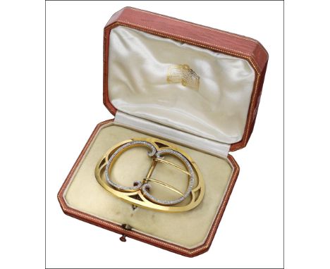 An early 20th century gold and diamond set buckle by Cartier, circa 1902, the bowed oval frame with inner twin C-scrolls set 
