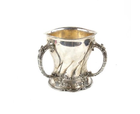 American silver three handled cup, of waisted form, with ribbon tied reeded handles and scroll cast base, engraved with monog
