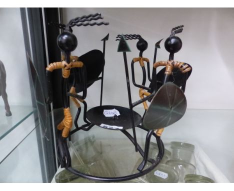 FOUR METAL AFRICAN FIGURES DANCING AROUND PRICKET CANDLESTICK