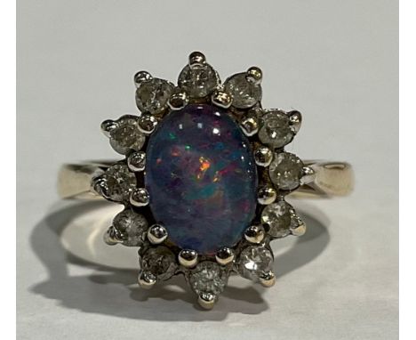 A 9ct gold opal doublet and diamond ring, the central polished oval stone surrounded by twelve brilliant cut stones, size K, 