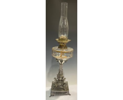 A late 19th century pewter oil lamp, the square base cast with mythical seahorses, clear glass reservoir, globular acid etche