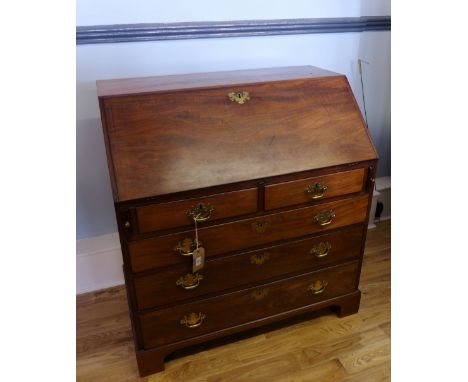 A George III mahogany bureau having a fall front top enclosing fitted interior over two short drawers and three long graduati