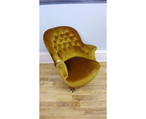 A late Victorian button back easy chair upholstered in green fabric, raised on turned supports and ceramic castors.