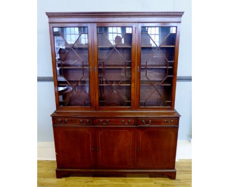 A mahogany bookcase cabinet having a dentil cornice over three astragal glazed panel doors enclosing three adjustable shelves