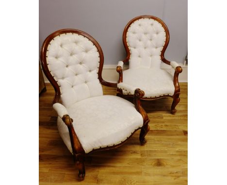 A pair of reproduction mahogany framed button back open arm chairs upholstered in a white floral fabric raised on moulded fee