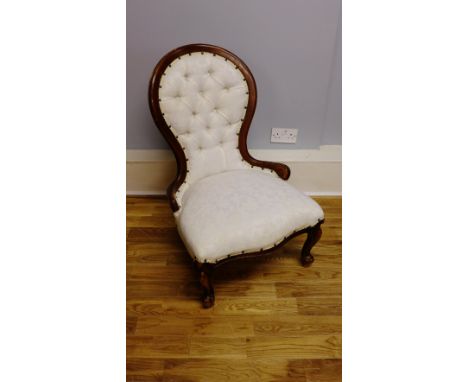 A reproduction mahogany framed button back lounge chair upholstered in a white floral fabric raised on moulded feet