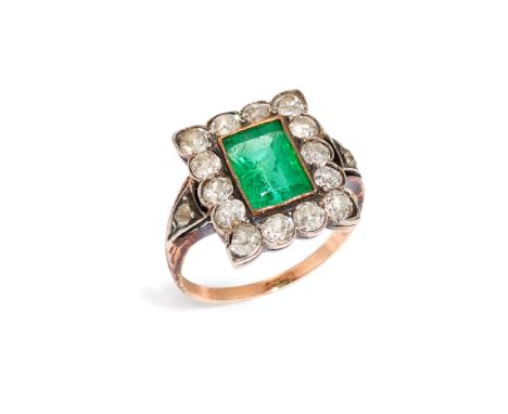An early 20th century silver and gold emerald and diamond cluster ring, composed of a central rectangular step-cut emerald, m