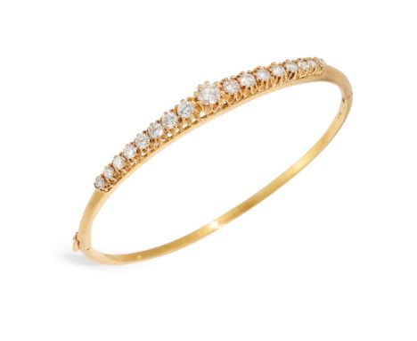 An 18ct gold diamond set hinged bangle, the upper half claw set with a row of graduated brilliant cut diamonds, with an estim