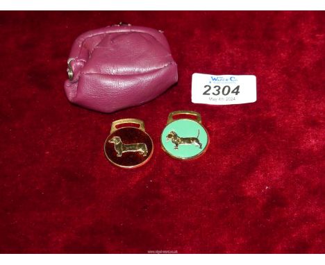 A red leather Purse containing two enamel dachshund tags.