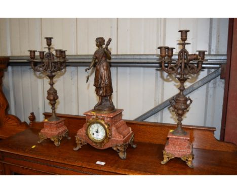 A rouge marble and spelter figural two hole clock with a pair of matching garnitures, key and pendulum on rostrum