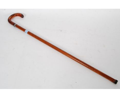 A good quality 20th century malacca and silver collared walking stick having an amber resin crook shaped handle to the top