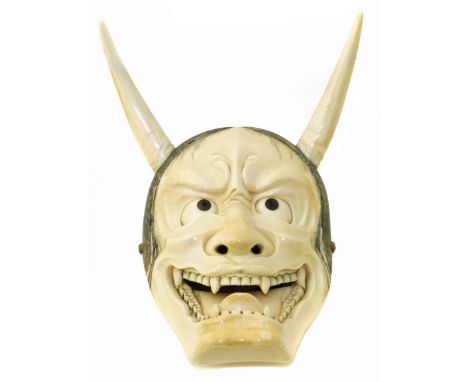 A Japanese Meiji Period carved ivory mask netsuke depicting Hannya, typically carved with bared teeth and horns, signed, dime