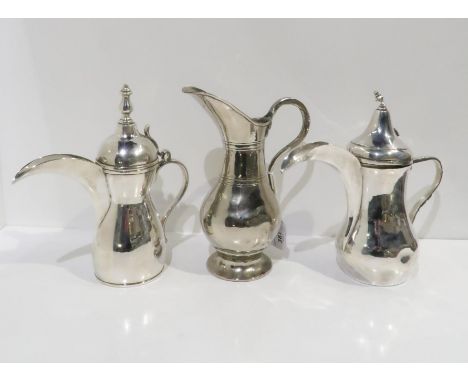 A Persian white metal Dallah coffee pot, with shell thumbpiece, and another, and a white metal pitcher, of inverted baluster 