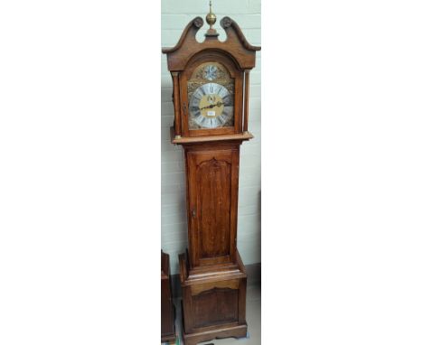 A period style oak longcase clock with brass dial and fielded panel door with triple weight driven chiming movement 