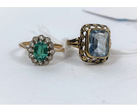 A yellow metal dress ring stamped 9ct set with central green stone, surrounded by clear stones, 2.4gm; an ornate dress ring s