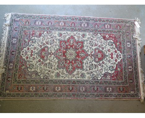 A 20th century hand knotted Eastern rug, foliate design borders with pink and cream field, central medallion with foliate des