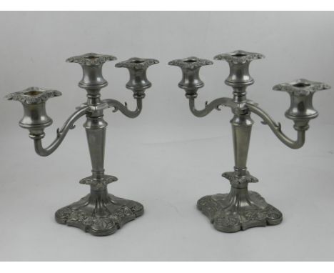 A pair of silver plated three light candelabras, having scrolling end arms and foliate square bases, stamped Made in England 