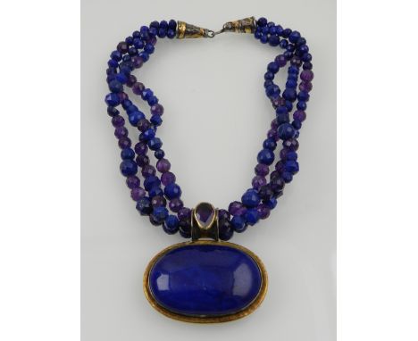 A silver, lapis lazuli and amethyst pendant of oval form, suspended on triple strands of faceted lapis and amethyst beads. 