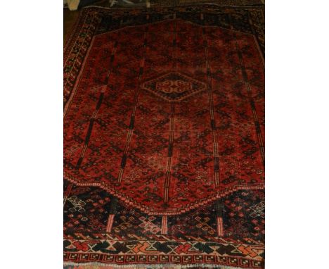 A red ground Caucasian carpet, decorated with hexagonal medallions to centre on a geometric patterned ground, multi-bordered,