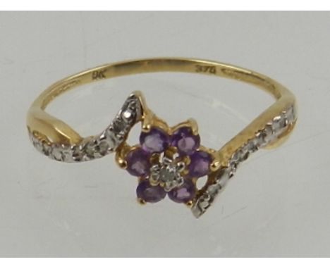 A 9 carat yellow gold, diamond, and amethyst floral crossover ring, the shoulders set with diamond accents.