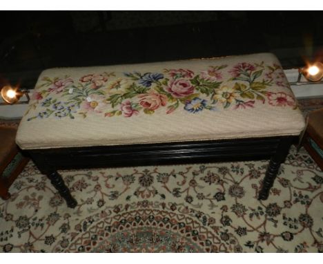 A 19th century ebonised duet piano stool, having tapestry upholstered hinged lid, raised on turned gun barrel supports. H: 50