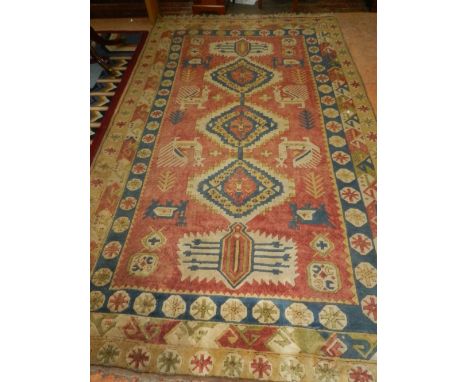 A red ground Kazak carpet, decorated with stepped medallions to centre, on a zoomorphic ground, within stylised floral border