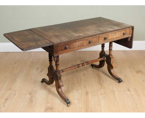 A 19th century mahogany sofa table with ring turned end supports and splaying legs terminating on hairy paw feet and casters,