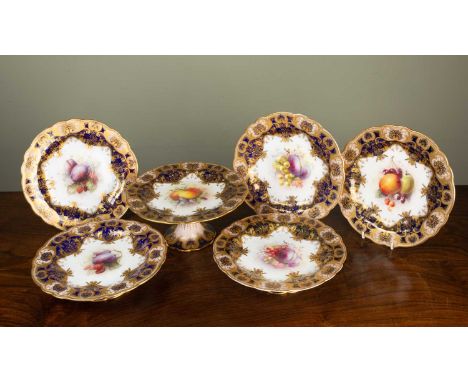 An early 20th century Royal Worcester porcelain part dessert service, each piece decorated with fruit and set within a gilt b