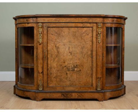 A Victorian walnut credenza with central door flanked by curving glazed display cabinets to either end, the credenza decorate