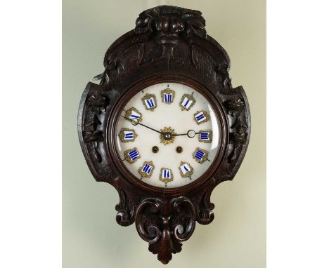 A continental carved oak wall clock with floral decoration, the circular marble dial set with enamel numberals, the movement 