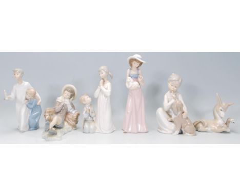 A group of four Lladro porcelain figures to include a young leaning on a log with a bird upon his feet, a figure of a donkey,