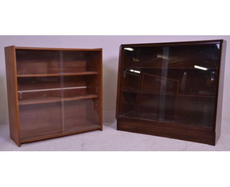 Two vintage 20th Century closed teak bookcase shelving units each having two shelves with glazed sliding cabinet drawers. One