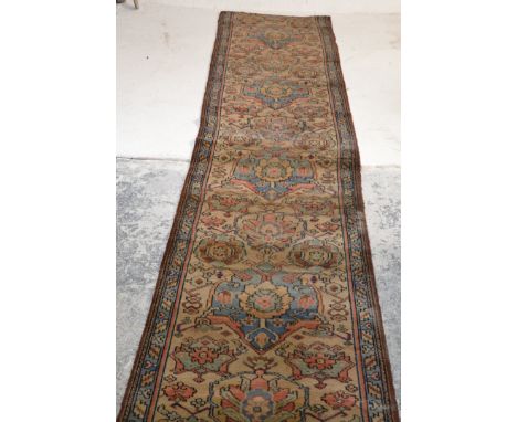 A 20th Century Persian Islamic runner floor carpet rug having a brown ground with blue medallions and floral decoration borde