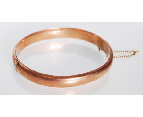 An early 20th Century hallmarked 9ct gold bangle bracelet having engraved scrolled foliate decoration, having a hinge opening