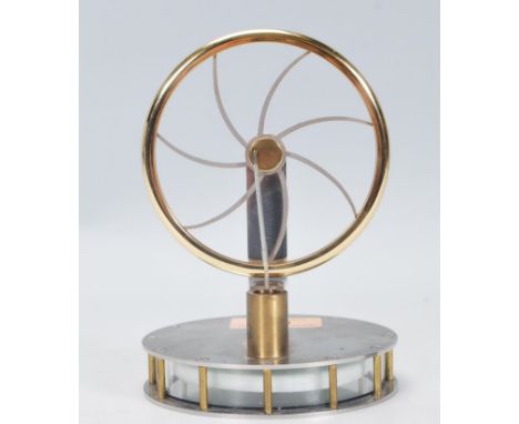 A desktop miniature stirling engine having a round chromed metal base with glass sides revealing moving mechanism within, hav