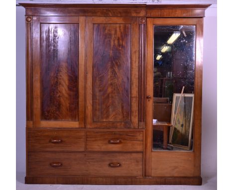 A large 19th Century Victorian mahogany triple wardrobe compactum being raised on a plinth base with flared cornice having a 