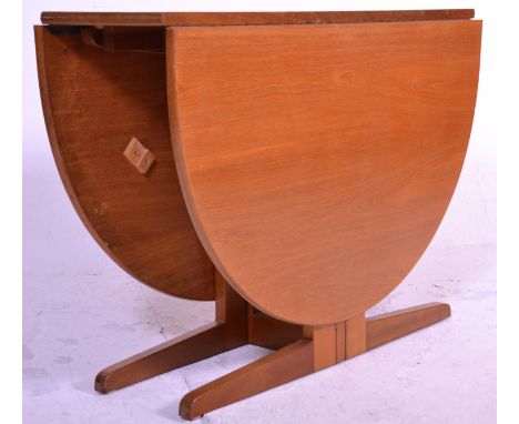 A mid century teak wood drop leaf dining table being raised on splayed legs with half moon shaped leaves rising on a gate leg