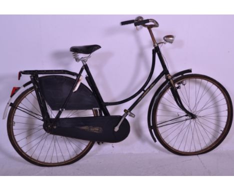 A vintage retro 20th Century fixed gear bike having a black tubular frame, a pannier rack to the back wheel along with mud gu