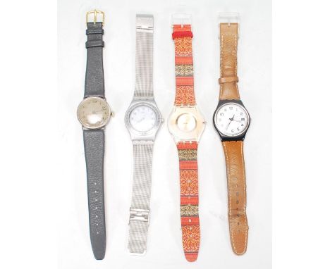 A group of three Swatch watches to include a silver tone bracelet watch, a brown leather strapped watch with a white enamelle
