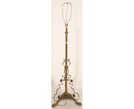 A vintage early 20th Century converted to electric brass floor standing lamp having a decorative brass moulded scroll base wi