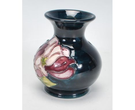 A Moorcroft vase of squat bulbous form. Tubelined decorated in the purple and white Magnolia pattern. Impressed and painted m