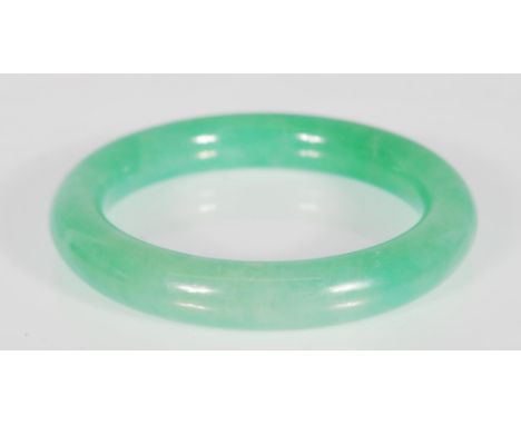 A 20th Century Chinese green jade bangle of round form. Interior diameter 5.5 cm. Measures 7.5 cm x 8 cm.