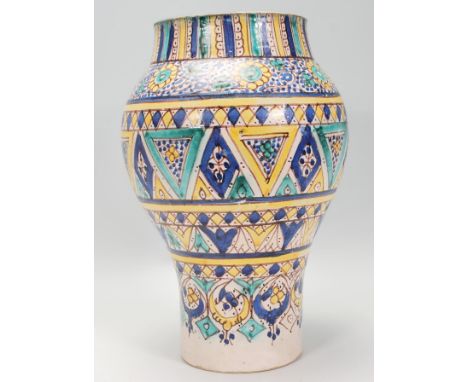 A late 19th / early 20th Century Moroccan pottery vase of waisted form having hand painted patterning decorated in blue, gree