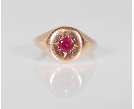 A 9ct rose gold signet ring set with a central round cut red stone with engraved star design surround. Stamped 9ct. Gross wei