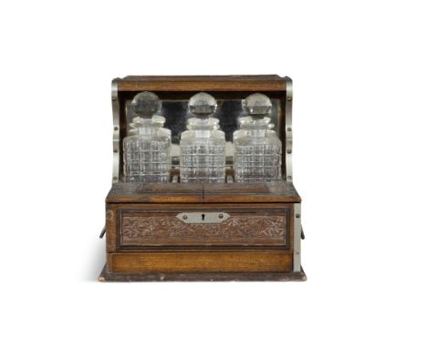 A VICTORIAN GILT-METAL MOUNTED OAK TANTALUS, LATE 19TH CENTURY,With three cut-glass decanters, the mirror back above a fronta