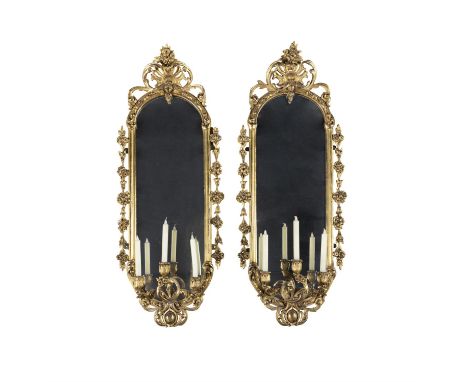A PAIR OF GILTWOOD FRAMED ELONGATED OVAL GIRANDOLE WALL MIRRORS, with surmounted stylised leaf decoration, the sides with ind