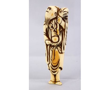 A LARGE JAPANESE EDO PERIOD CARVED IVORY NETSUKE OF A SENNIN, stood looking aloft holding a sack over his shoulder, himotoshi