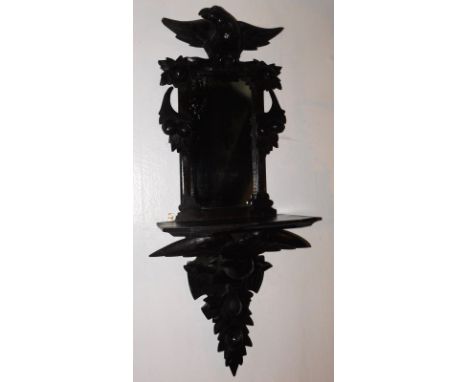 A 19thC Continental ebonised and carved mirrored wall shelf, decorated with birds and acorns, 105cm high.